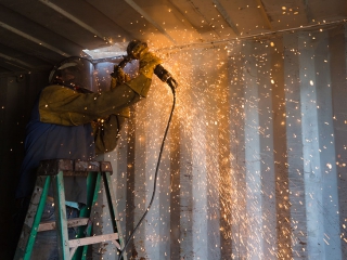 Container Stop worker cutting out section of shipping container